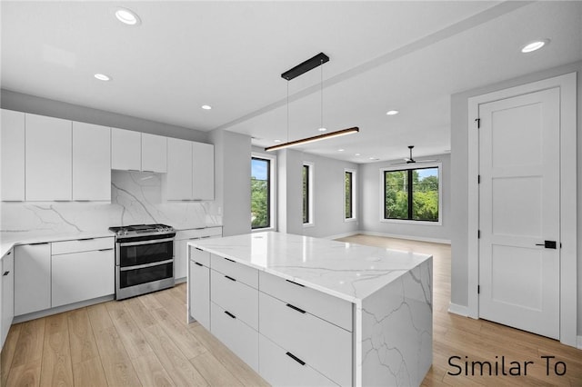 kitchen with pendant lighting, a center island, range with two ovens, and white cabinets