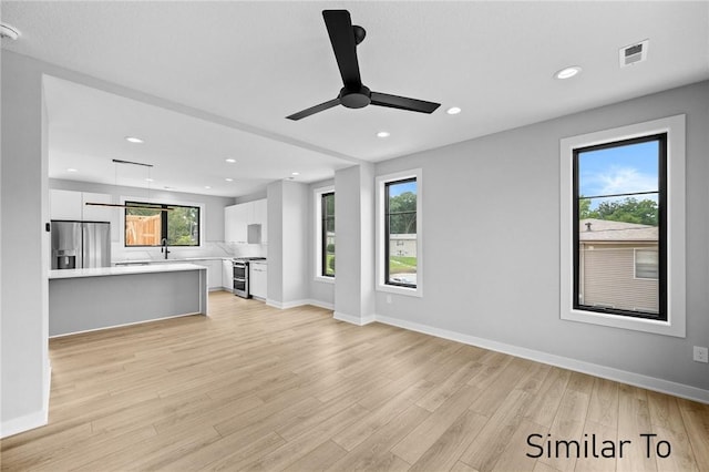 unfurnished living room with sink, ceiling fan, and light wood-type flooring