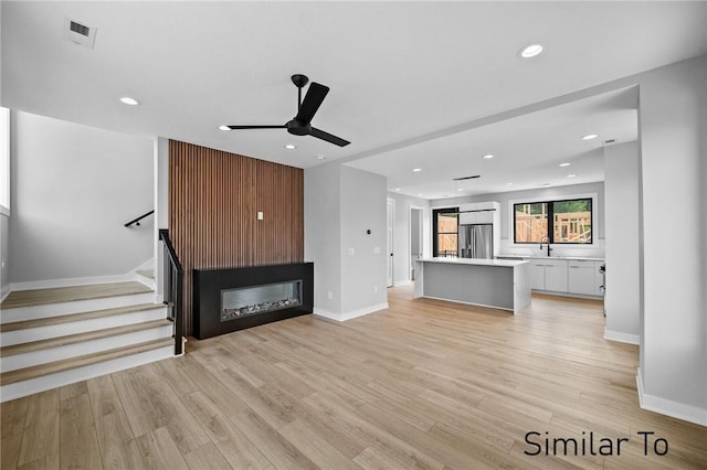 unfurnished living room featuring sink, light hardwood / wood-style flooring, and ceiling fan