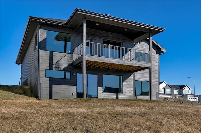 back of house featuring a balcony and a yard