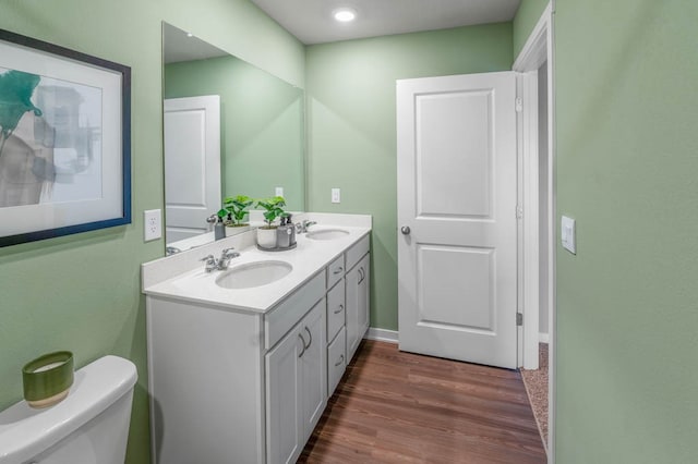 bathroom with hardwood / wood-style floors, double vanity, and toilet