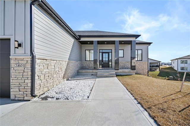 doorway to property featuring covered porch and a yard