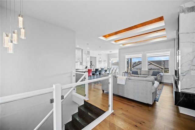 living room featuring wood-type flooring, a skylight, and beam ceiling