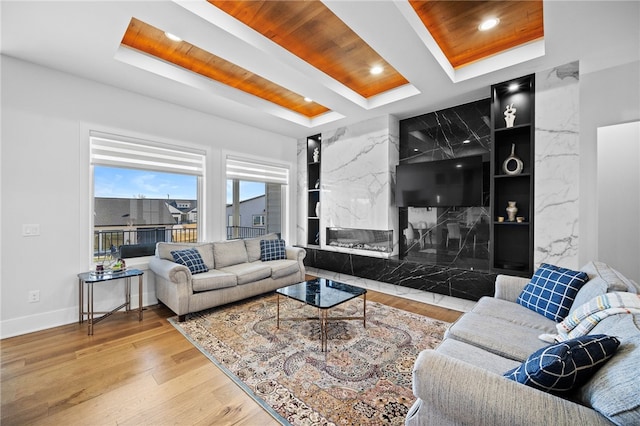 living room featuring wood-type flooring, beam ceiling, built in features, wooden ceiling, and a fireplace