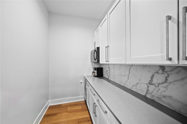 kitchen with white cabinets, tasteful backsplash, and light hardwood / wood-style flooring