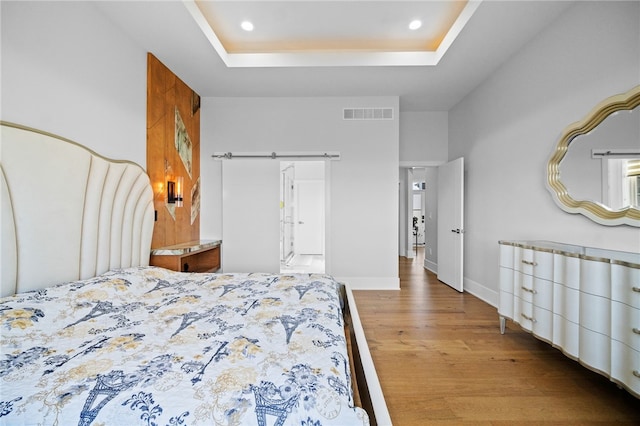 bedroom featuring hardwood / wood-style flooring and a tray ceiling