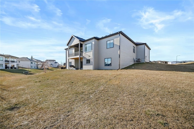 back of property featuring a balcony, central AC, and a lawn