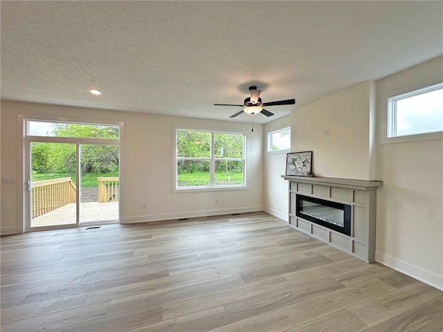 unfurnished living room with ceiling fan, a textured ceiling, and light wood-type flooring