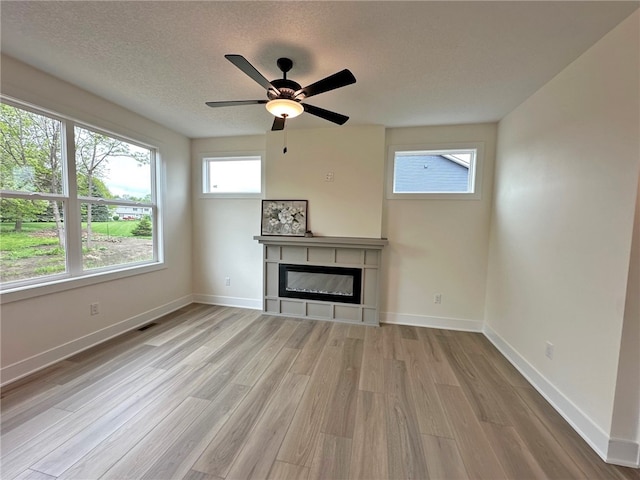 unfurnished living room with a textured ceiling, light hardwood / wood-style flooring, and ceiling fan