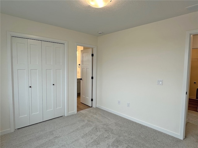 unfurnished bedroom featuring a textured ceiling, light colored carpet, and a closet