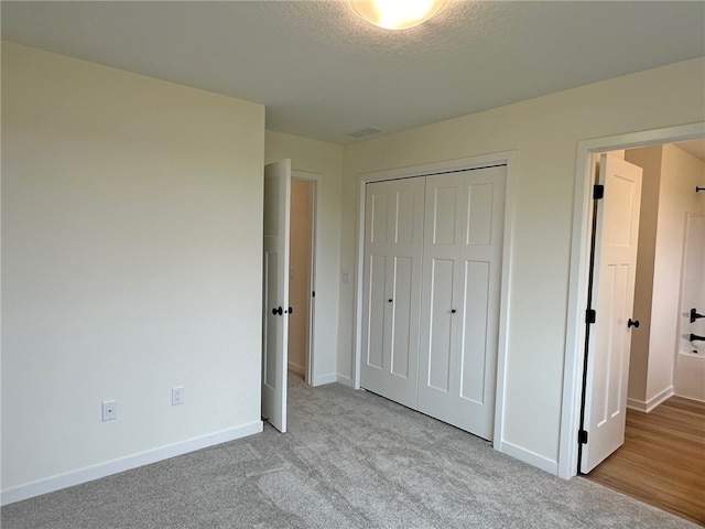 unfurnished bedroom with a textured ceiling, light carpet, and a closet