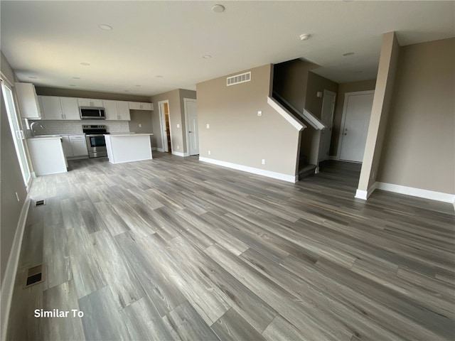 unfurnished living room with hardwood / wood-style floors and sink