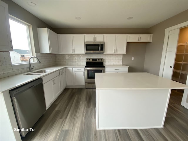 kitchen with dark hardwood / wood-style floors, stainless steel appliances, backsplash, sink, and white cabinets