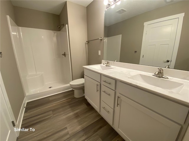 bathroom featuring vanity with extensive cabinet space, toilet, hardwood / wood-style floors, walk in shower, and double sink