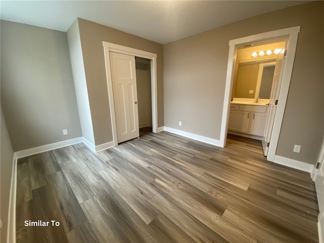 unfurnished bedroom featuring a closet, ensuite bathroom, and hardwood / wood-style floors