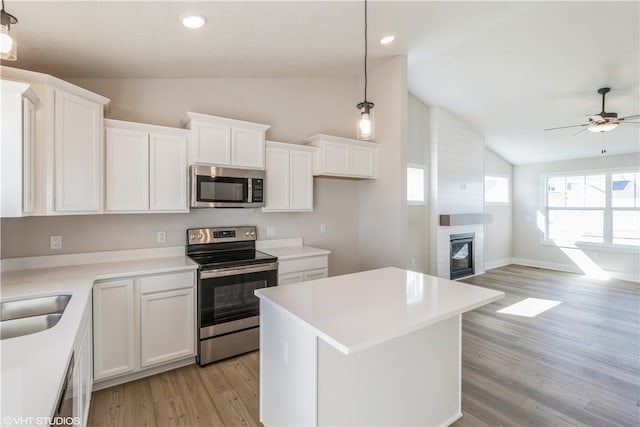 kitchen with white cabinetry, stainless steel appliances, pendant lighting, and vaulted ceiling