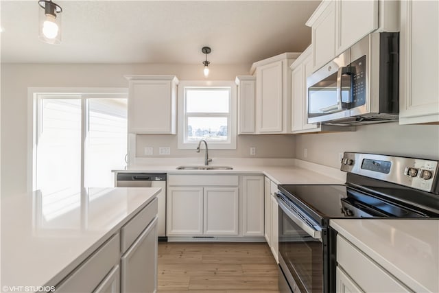 kitchen featuring stainless steel appliances, sink, light wood-type flooring, and white cabinets