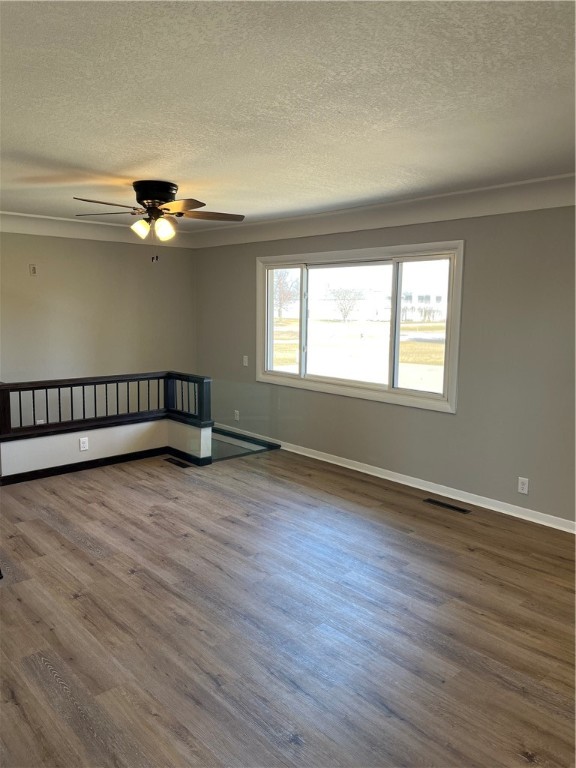 empty room featuring ceiling fan, a textured ceiling, and dark hardwood / wood-style flooring