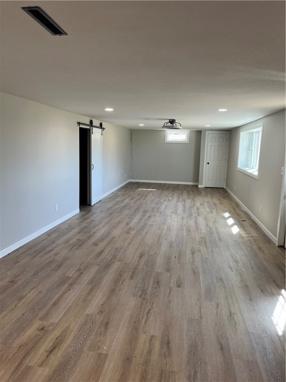 basement featuring a barn door and hardwood / wood-style flooring