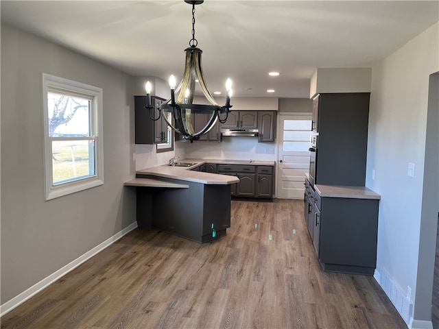 kitchen featuring an inviting chandelier, gray cabinets, wood-type flooring, and sink