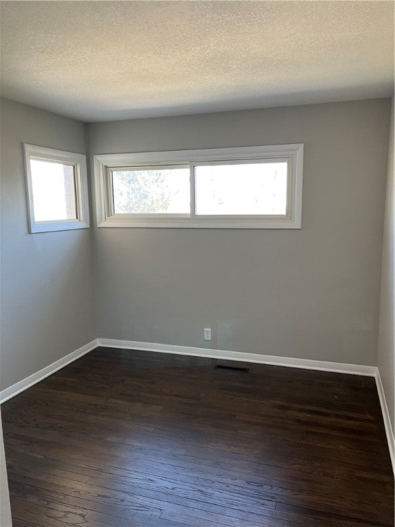 spare room with dark hardwood / wood-style floors and a textured ceiling