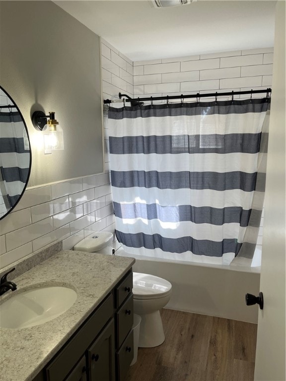 full bathroom featuring toilet, oversized vanity, tasteful backsplash, hardwood / wood-style floors, and shower / tub combo with curtain