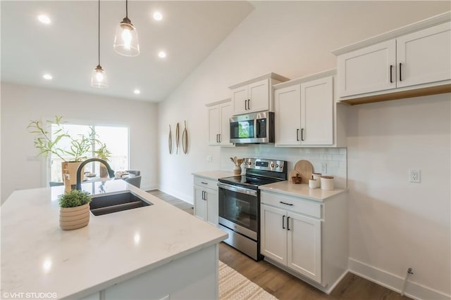 kitchen featuring appliances with stainless steel finishes, sink, decorative light fixtures, light hardwood / wood-style flooring, and white cabinets