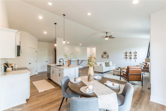 dining area with ceiling fan, sink, lofted ceiling, and light hardwood / wood-style flooring