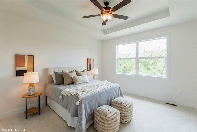 bedroom featuring a raised ceiling, ceiling fan, and light colored carpet