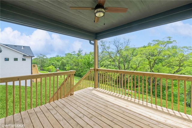 wooden terrace with a ceiling fan and a lawn