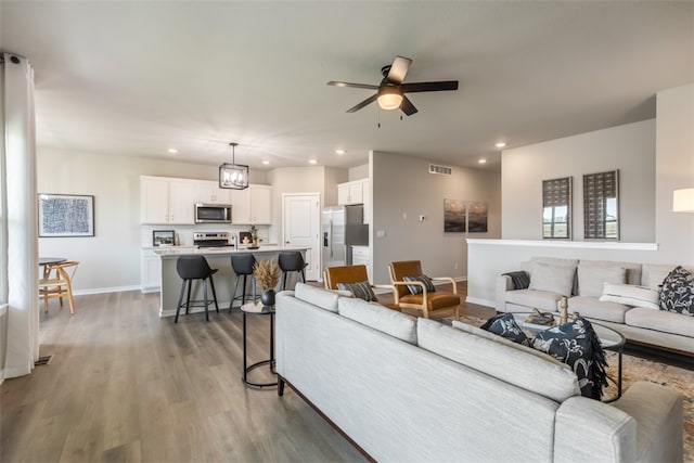 living room with dark wood-type flooring and ceiling fan