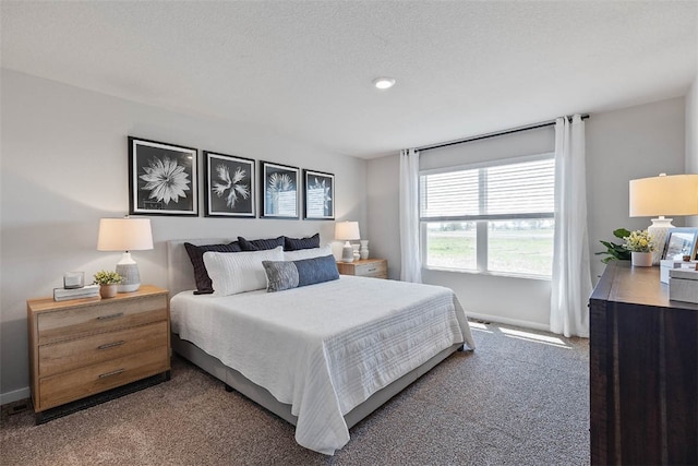 bedroom featuring a textured ceiling and dark carpet