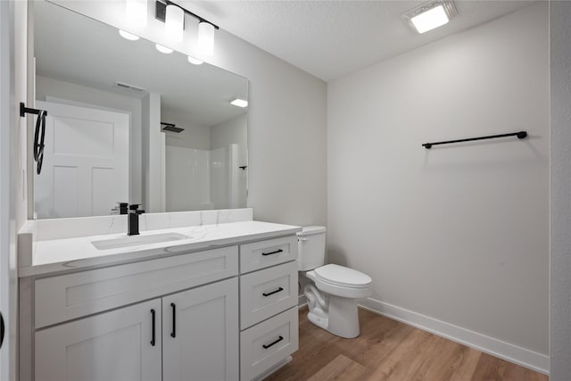 bathroom with a shower, hardwood / wood-style floors, a textured ceiling, toilet, and vanity