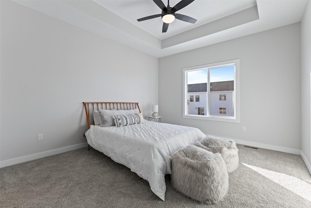 carpeted bedroom featuring a tray ceiling and ceiling fan