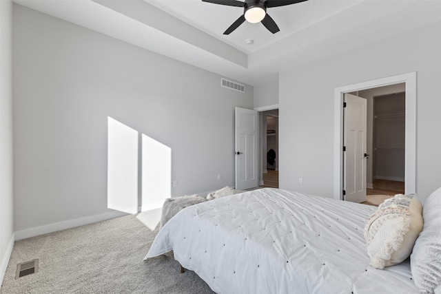 carpeted bedroom featuring a walk in closet, ceiling fan, and a closet