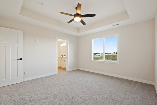 carpeted spare room featuring ceiling fan and a tray ceiling