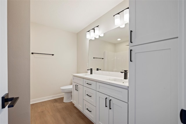 bathroom with wood-type flooring, vanity, walk in shower, and toilet