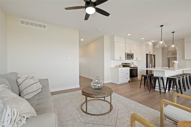 living room with ceiling fan and light wood-type flooring