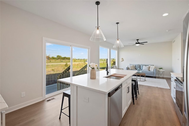 kitchen with sink, white cabinetry, hanging light fixtures, a center island with sink, and stainless steel appliances