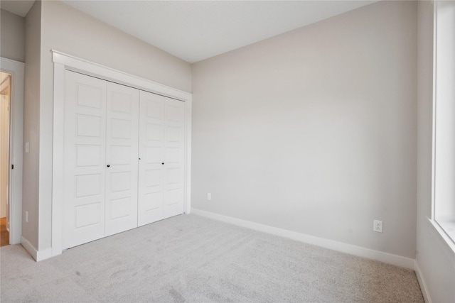 unfurnished bedroom with light colored carpet and a closet