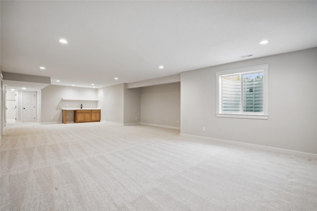 basement featuring sink and light colored carpet