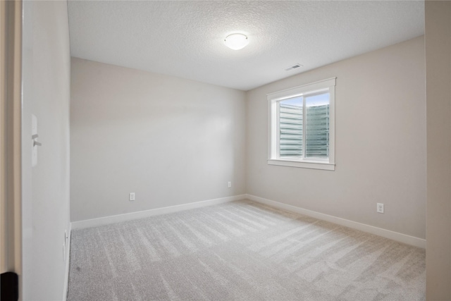 unfurnished room featuring light colored carpet and a textured ceiling