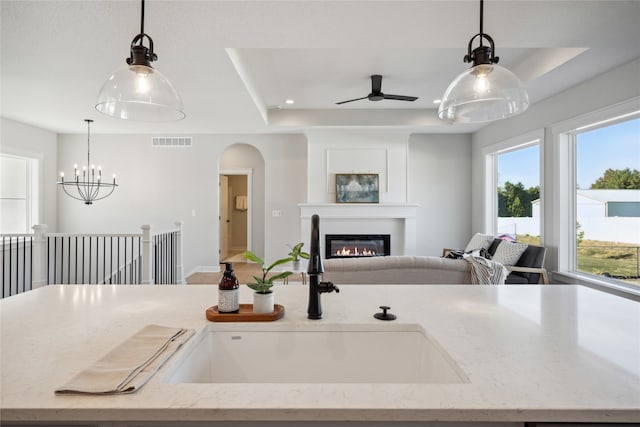 kitchen featuring sink, pendant lighting, and light stone counters