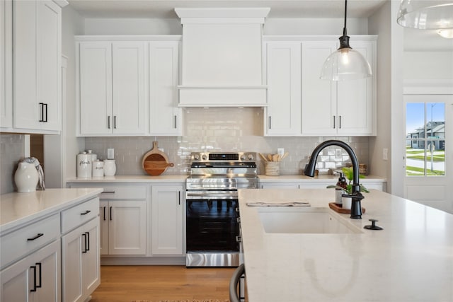 kitchen featuring electric stove, sink, pendant lighting, white cabinetry, and light wood-type flooring