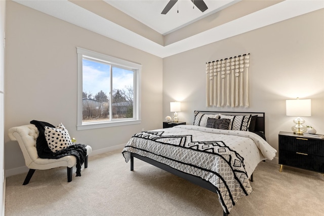 carpeted bedroom featuring a raised ceiling and ceiling fan