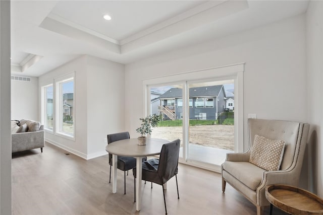 dining room with light hardwood / wood-style flooring and a tray ceiling