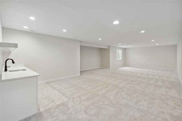 basement featuring sink and light carpet