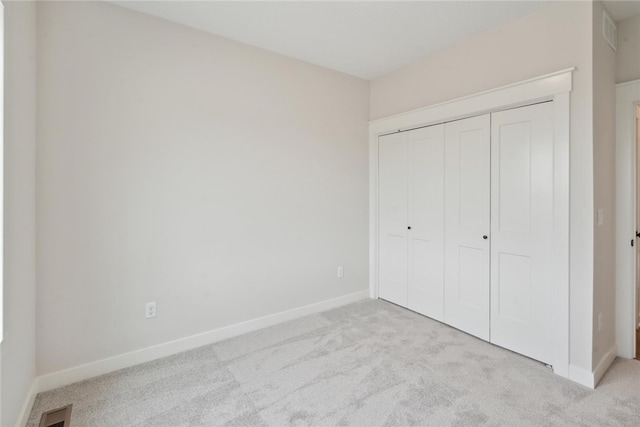 unfurnished bedroom featuring a closet and light colored carpet