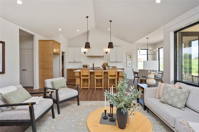 living area with recessed lighting, vaulted ceiling, light wood-style flooring, and an inviting chandelier