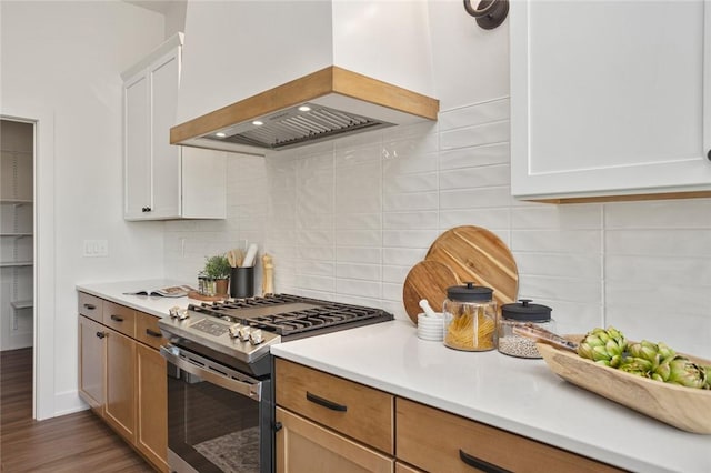 kitchen with custom exhaust hood, light countertops, backsplash, wood finished floors, and stainless steel gas range oven